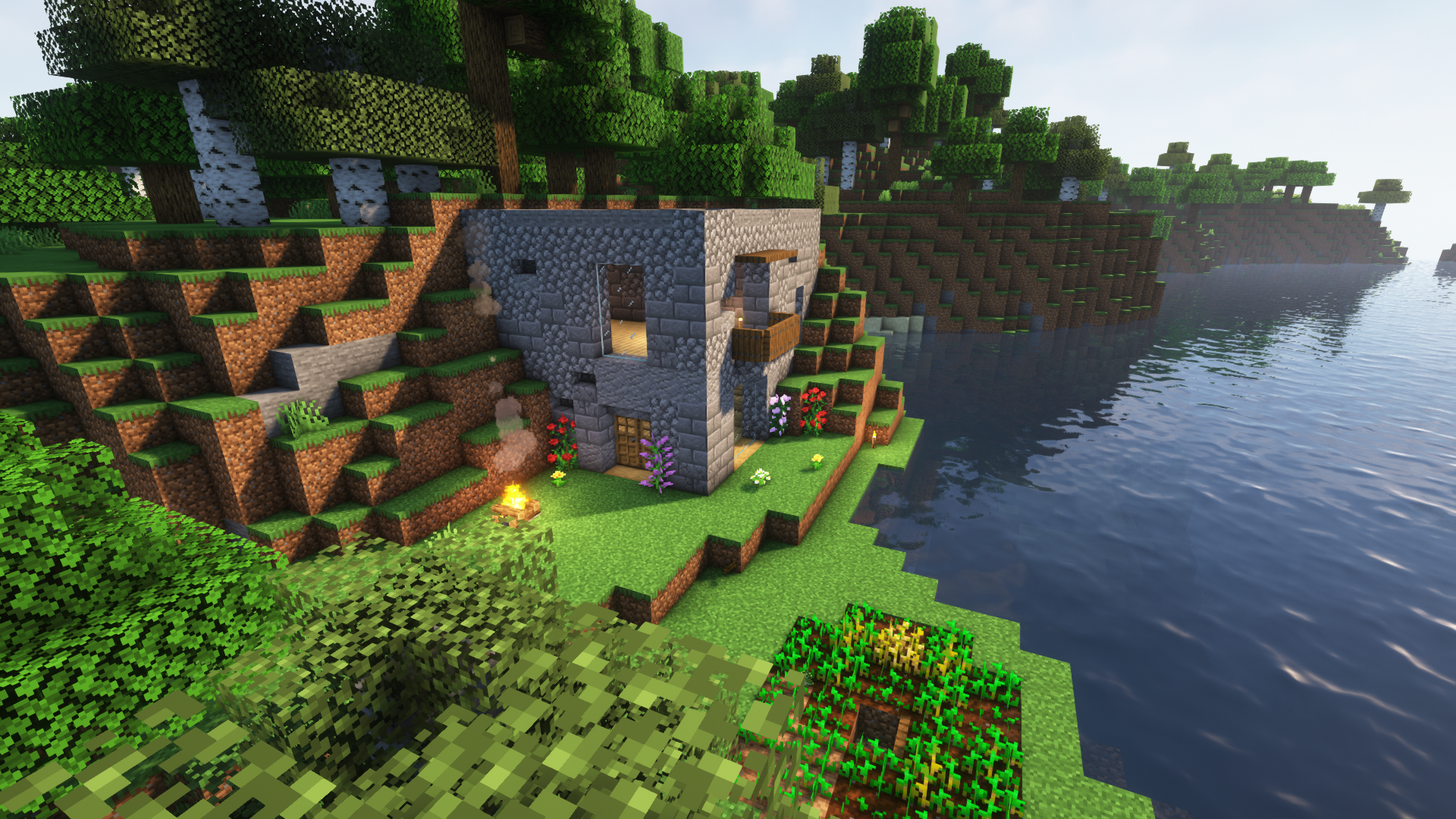 A cubic structure made of cobblestone, stone bricks, and other stone-type blocks. It has a small balcony made of spruce trapdoors overlooking the water.